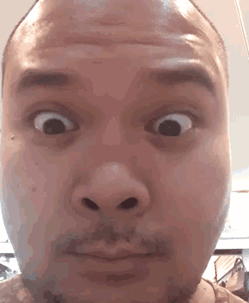 a man with a beard is making a funny face with his eyes wide open