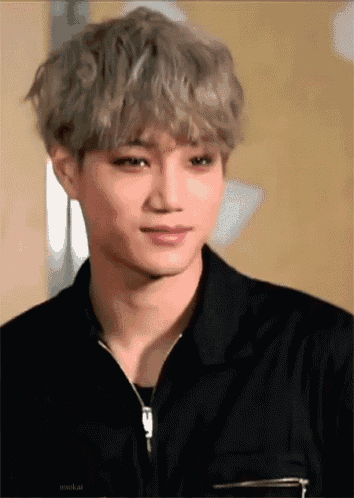 a young man with gray hair is wearing a black jacket and looking at the camera .