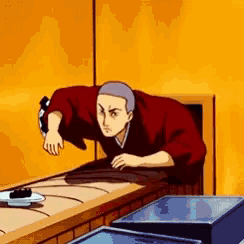 a man in a kimono is standing on a table in front of a wall .