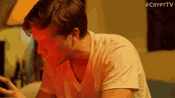a man is sitting in front of a computer with a red glow on his face .