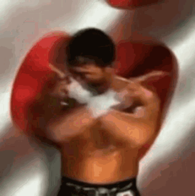 a man without a shirt is wearing boxing gloves and wrapping his hands .