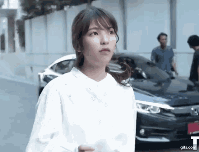 a woman is standing in front of a black car .