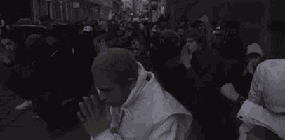 a man with green hair is kneeling down in front of a crowd of people with the words sorry for your loss written above him .