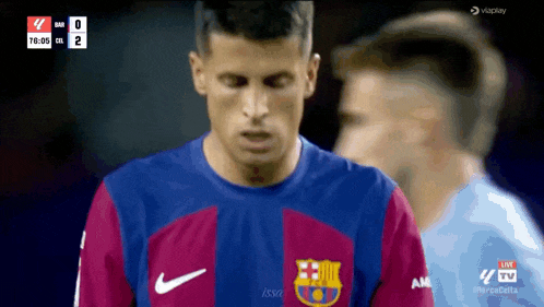 a soccer player wearing a barcelona jersey looks down at the scoreboard