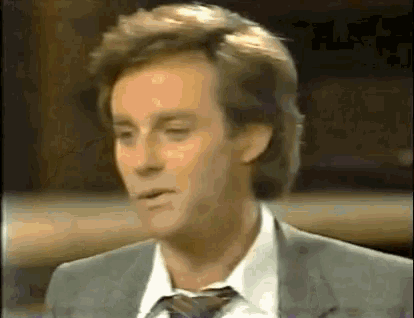 a man is wearing a suit and tie and making a funny face .