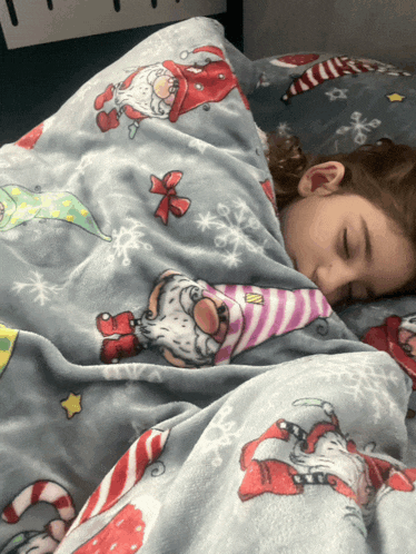 a child is sleeping under a christmas blanket