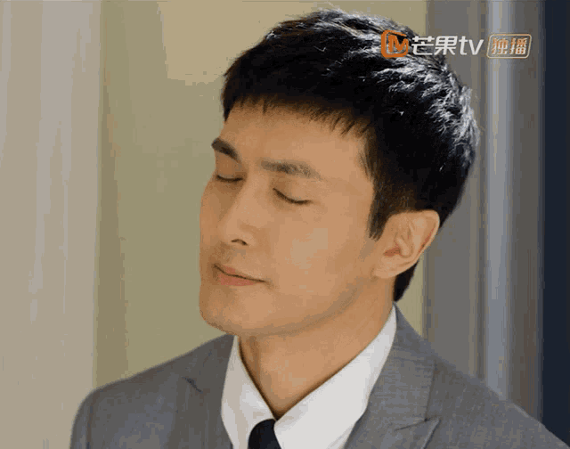 a close up of a man 's face with a chinese tv logo behind him