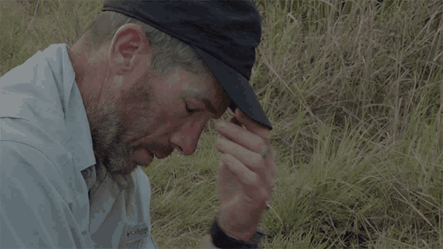 a man wearing a columbia shirt covering his face