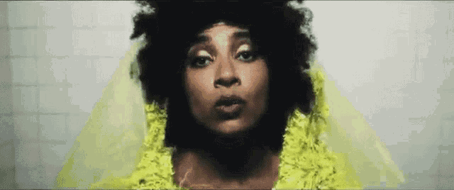 a woman with curly hair is wearing a yellow veil and a yellow dress .