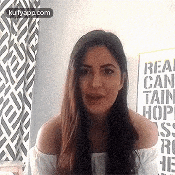 a woman with long hair is standing in front of a sign that says `` real can tain hop '' .