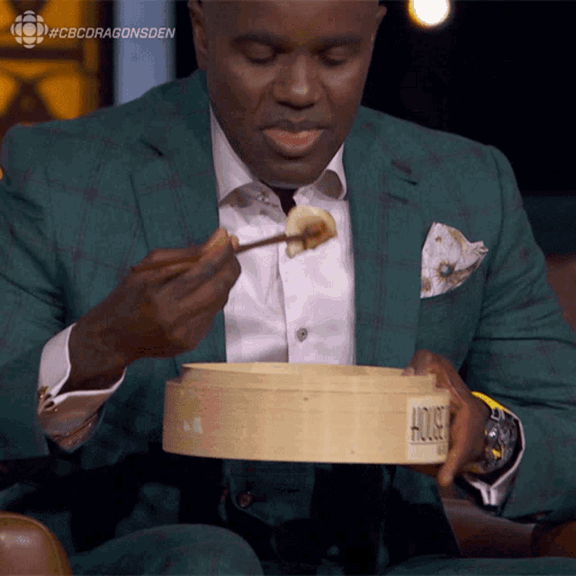a man in a green suit is eating food from a wooden box that says house