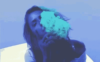 a woman is smoking a cigarette with blue smoke coming out of her mouth and nose .