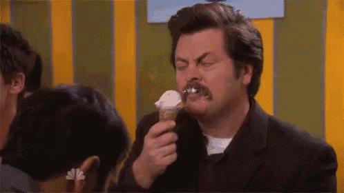 a man with a mustache is eating an ice cream cone with his mouth open .