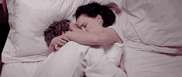 a man and a woman are hugging each other while sleeping on a bed