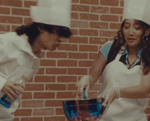 a woman in a chef 's hat stirs a bowl with a spoon