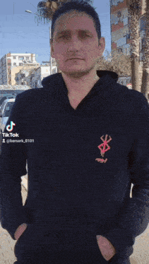 a man is wearing a black hoodie with a red logo on it