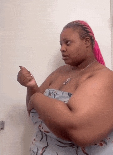 a woman with pink braids and a necklace with the letter t on it