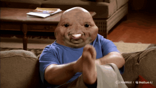 a man is sitting on a couch with his feet crossed and his face looks like a frog