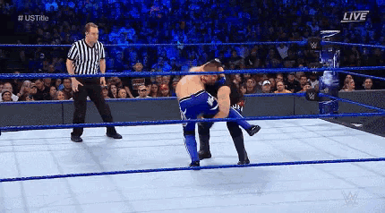 two men are wrestling in a wrestling ring with a referee in the background .