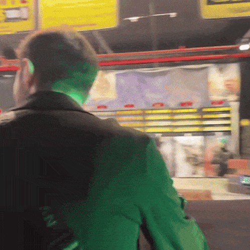 a man in a green jacket is standing in front of a sign that says fan