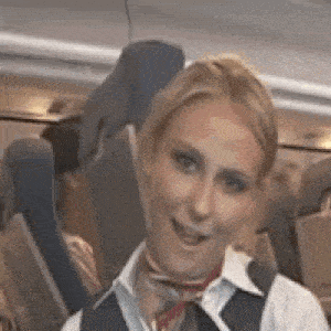a woman wearing a vest and scarf is smiling on a plane .