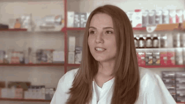 a woman in a white lab coat is standing in front of a pharmacy .