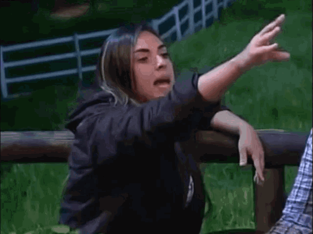 a woman is pointing her finger at something while sitting on a bench .