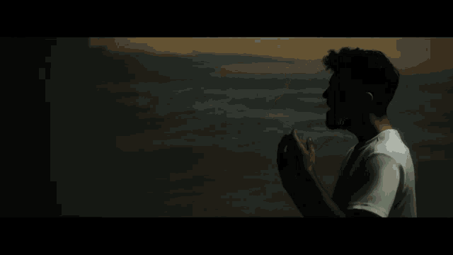 a man in a white shirt is standing in the dark