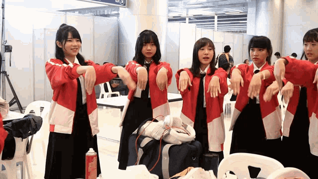 a group of young girls are stretching their arms in front of a sign that says ' a ' on it