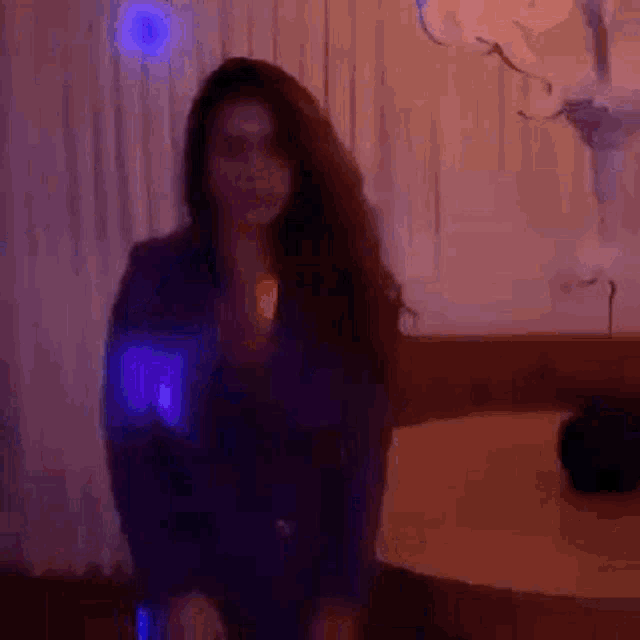 a woman in a purple dress is dancing in a dark room with purple lights .
