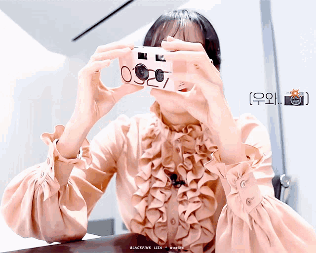 a woman in a pink ruffled shirt is taking a picture with a camera labeled blackpink lisa