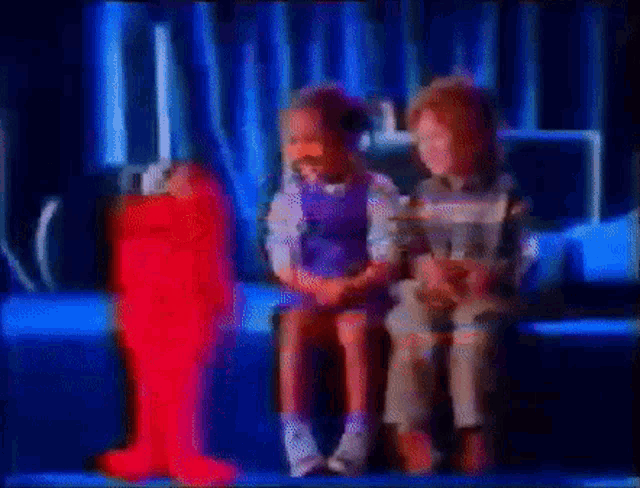 a boy and a girl are sitting on a couch with elmo .