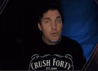 a man wearing a crush forty shirt holds his fist in the air