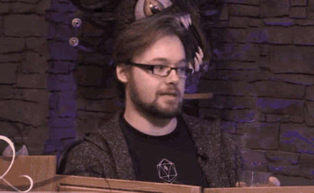 a man with a beard wearing glasses and a black shirt with a triangle on it