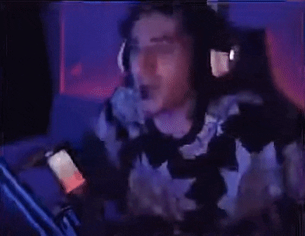 a man wearing headphones is playing a video game while holding a cell phone .