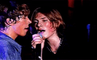 a couple of people singing into microphones with their eyes closed