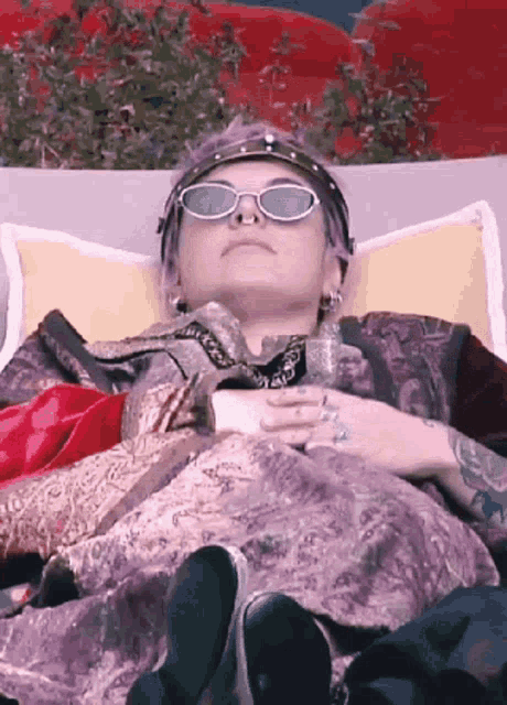 a woman wearing sunglasses is laying down on a couch