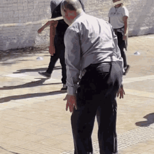 a man in a gray shirt and black pants stands on a sidewalk
