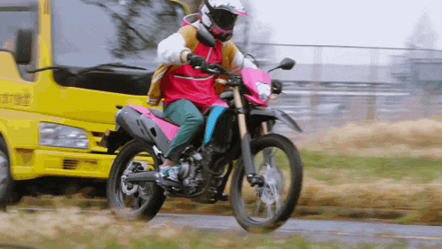 a person riding a motorcycle in front of a yellow truck that says ' a ' on it