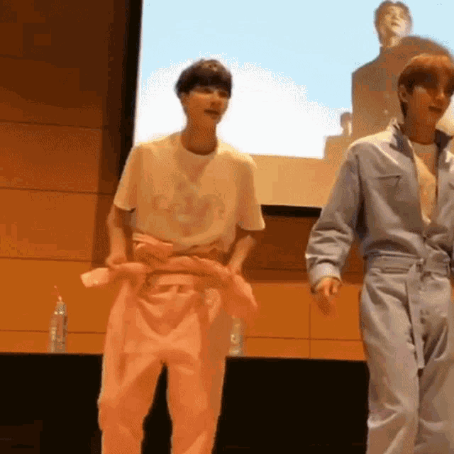 two young men are dancing in front of a large screen