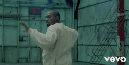 a man in a white sweatshirt is dancing with another man in a prison uniform .