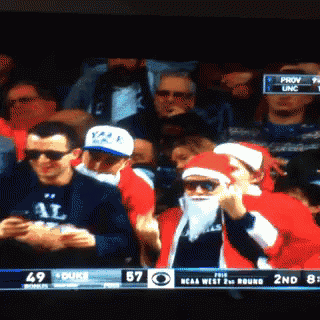 a man in a santa costume watches a game between duke and ncaa west