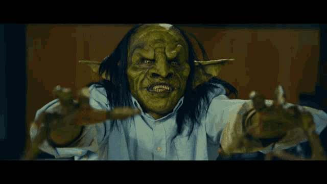 a man in a blue shirt with a green monster mask on his face