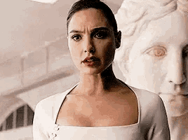 a woman in a white dress is standing in front of a statue of a woman .