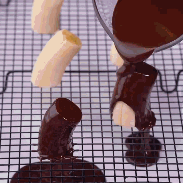 chocolate is being poured onto a banana on a cooling rack