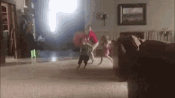 a group of children are playing in a living room with a light coming through the window .