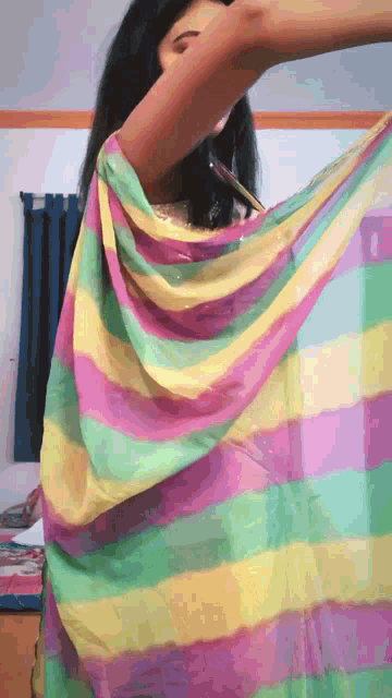 a woman is holding a rainbow colored blanket over her shoulder