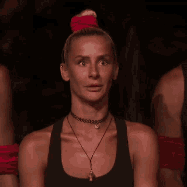a woman wearing a choker and a black tank top is making a surprised face