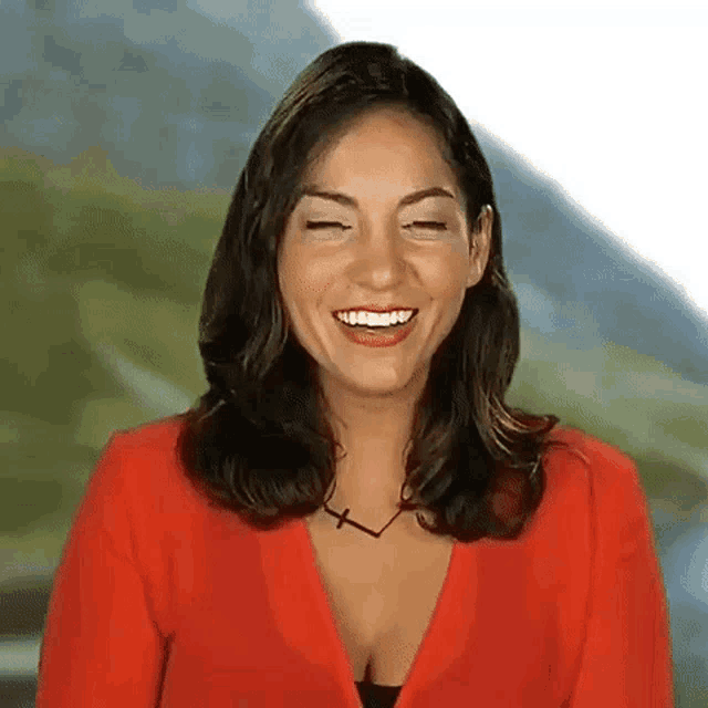 a woman in a red jacket is laughing with her eyes closed