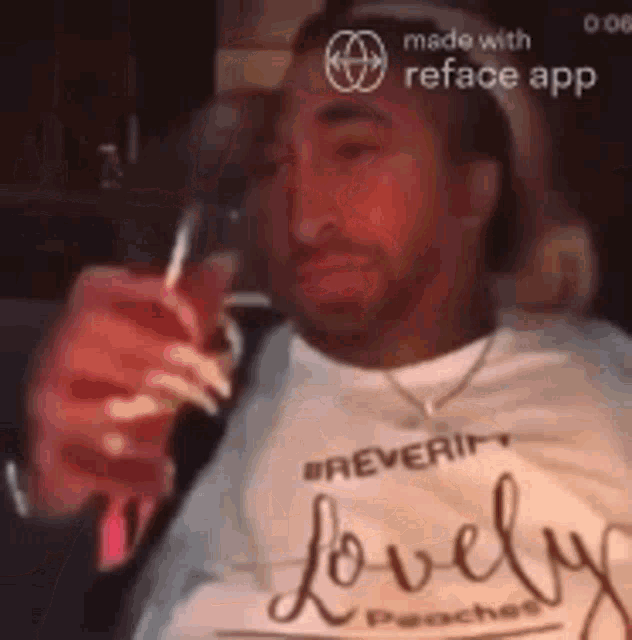 a man with long nails is holding a glass of wine and wearing a lovely shirt .